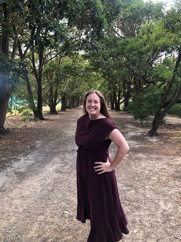Lyndall standing with hands on hips on a pathway with trees on either side.