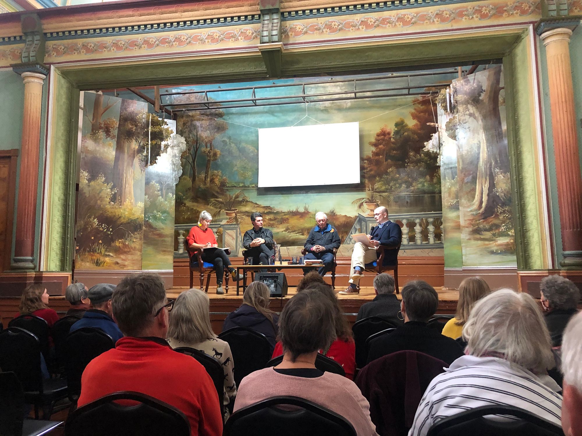 From left, Alex Kelly, Scott Ludlam, Ian Lowe and Timothy Lynch discuss Australia's future in the Town Hall at Clues. The Town Hall is a historic building and there is an old fashioned painted mural on the stage.