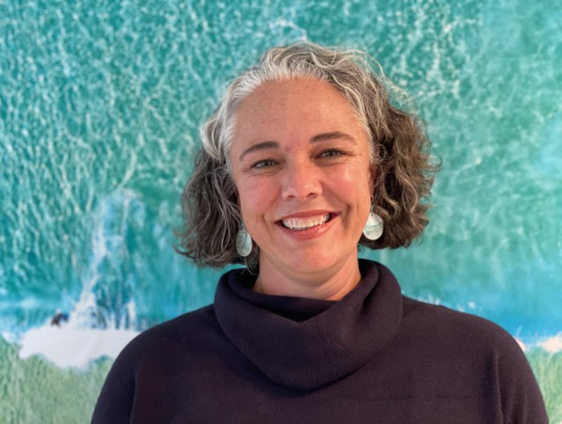 A photo of Virginia Richardson in front of a huge photo of the ocean