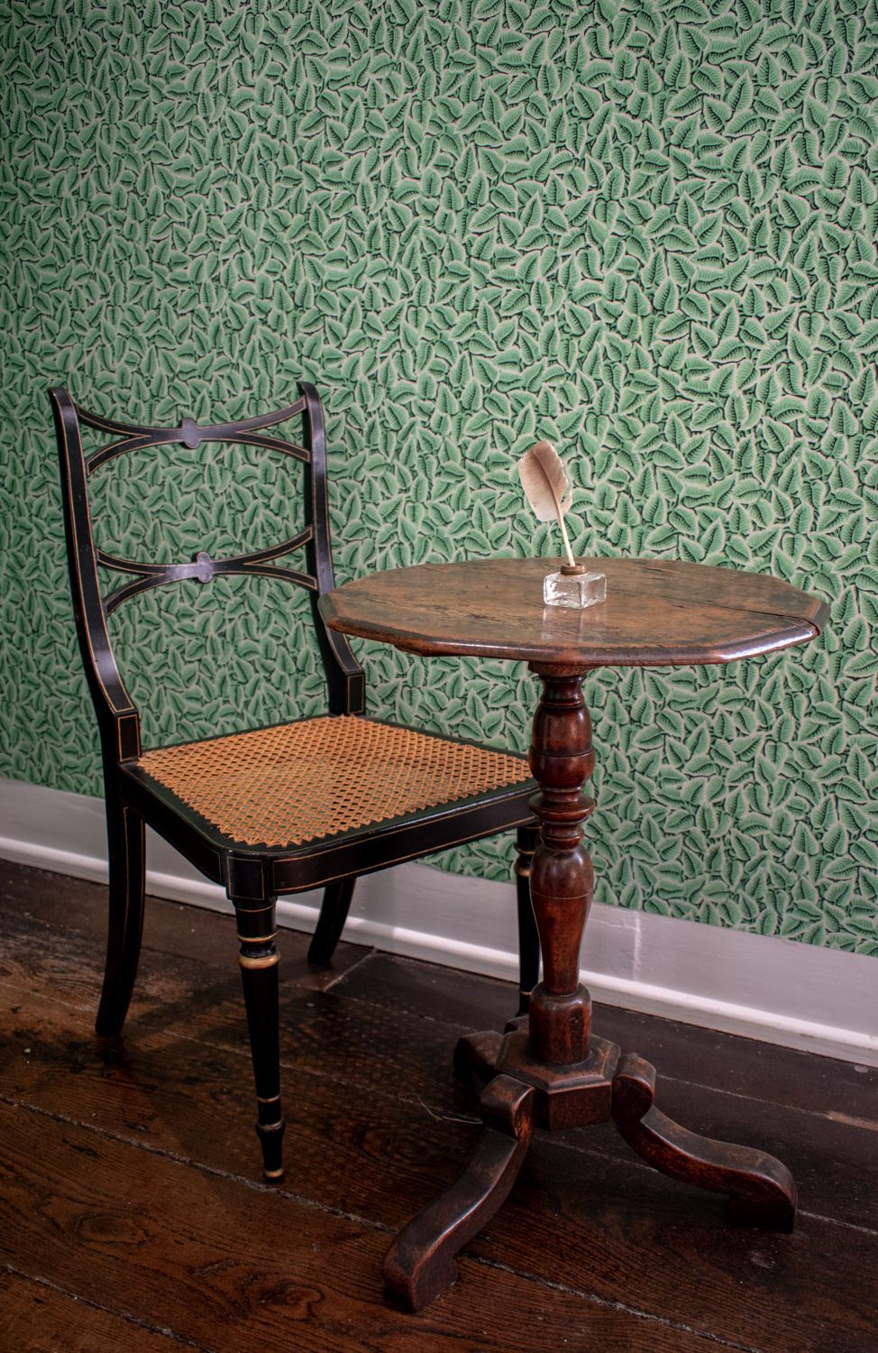 A small wooden table with a chair in a hallway with wooden floors.