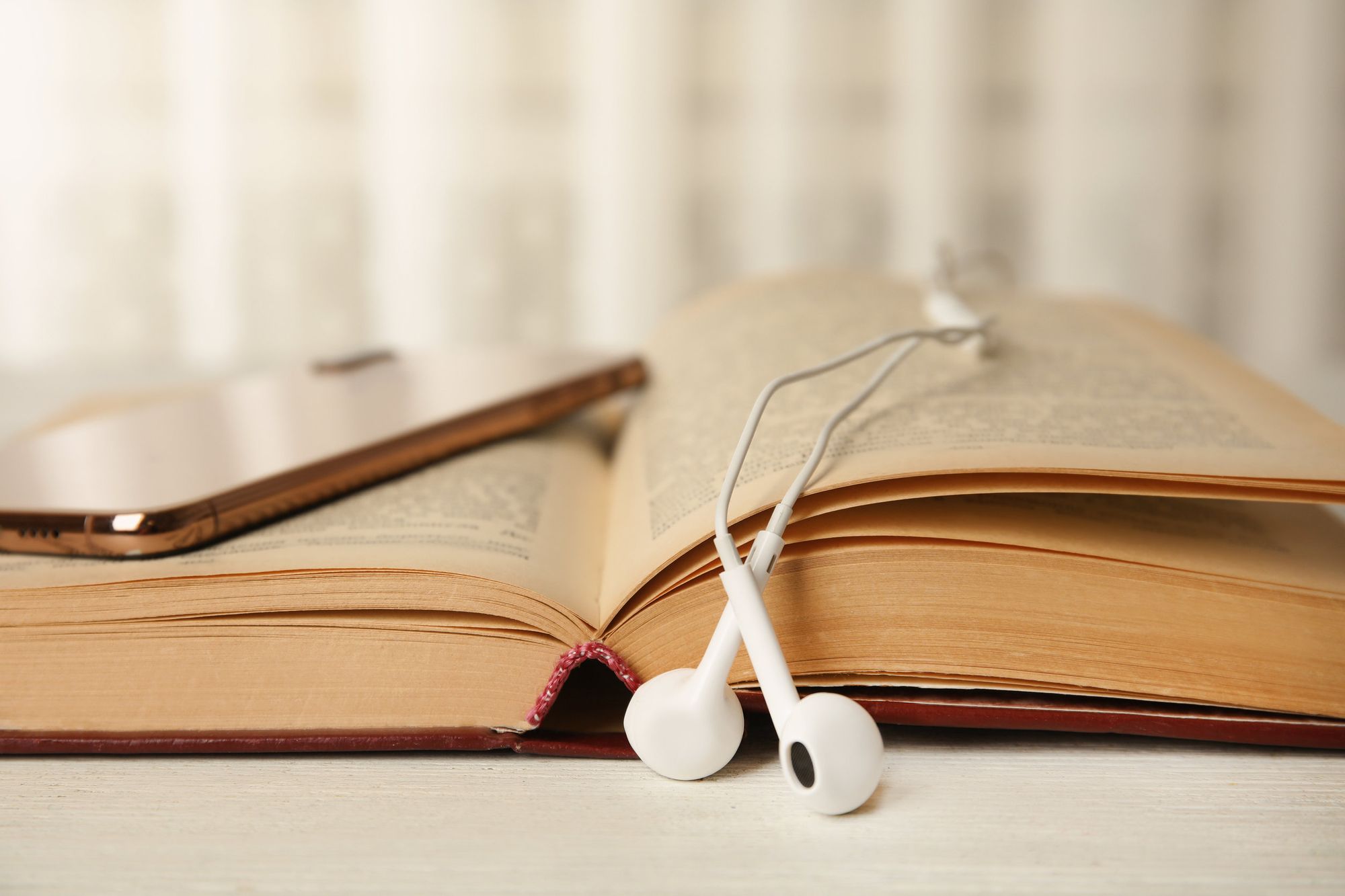 An open book with headphones and a phone on top.