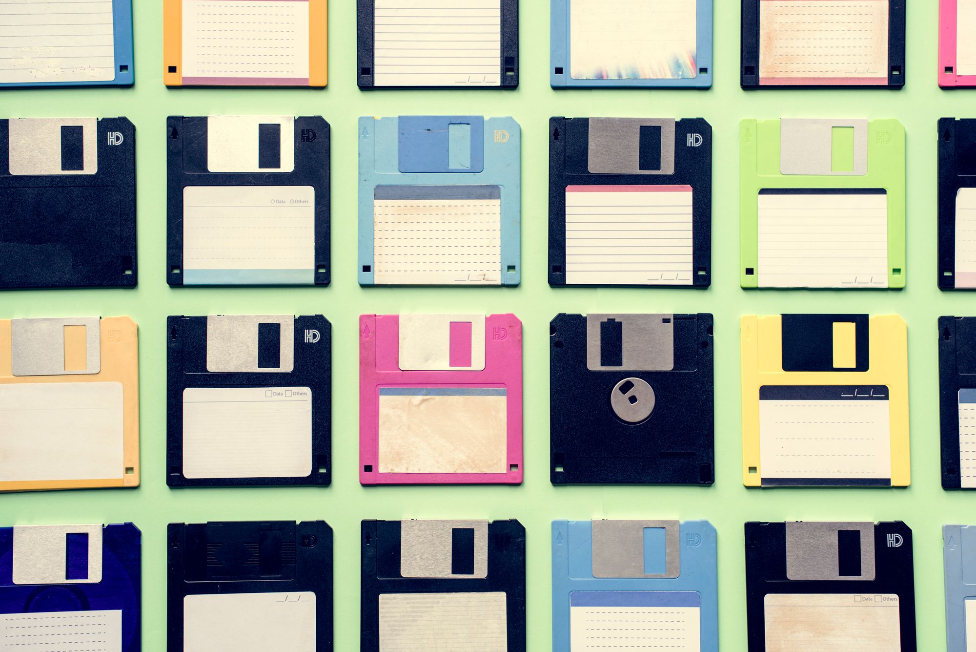 Old school floppy disks laid out on a pale green background. 