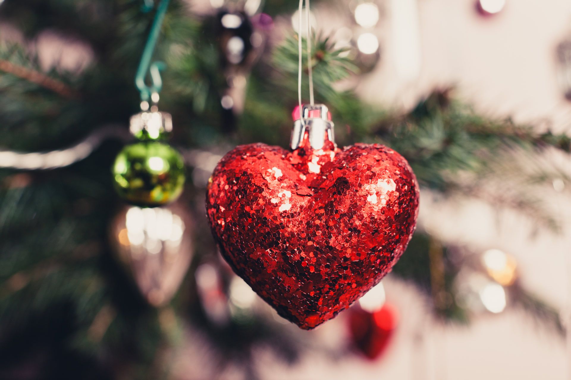 A sequinned, heart-shaped bauble on a Christmas tree.