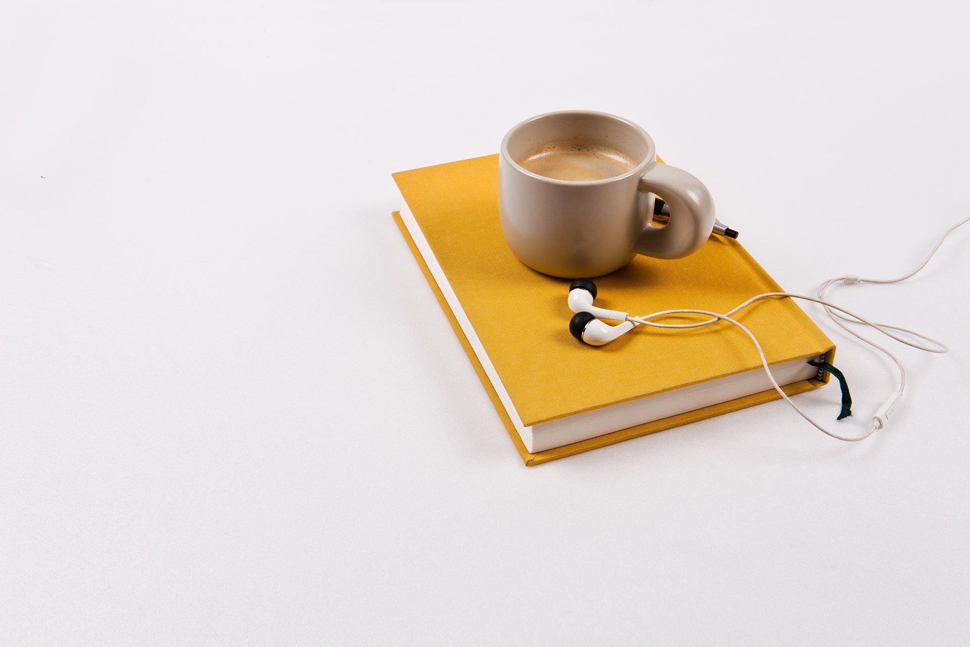 An orange hardcover journal with a coffee cup and some headphones. 