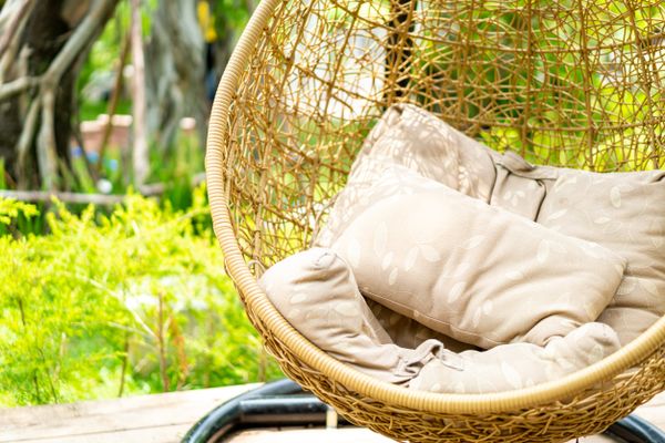 An egg chair with cushions with a garden in the background