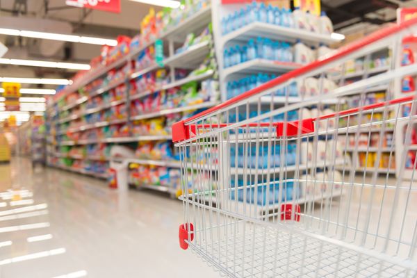 An empty shopping trolley heading toward a supermarket aisle. 