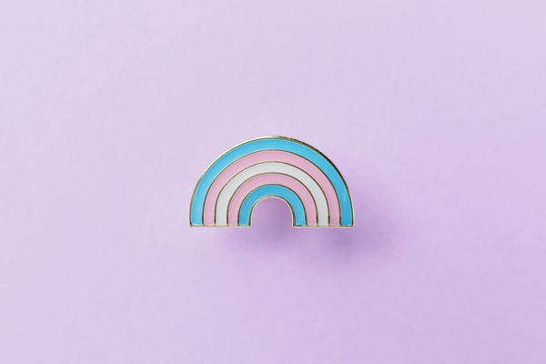 A rainbow pin on a purple background. 