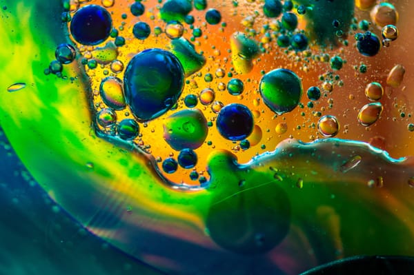 Abstract image of water and oil in bright greens, yellows and blues