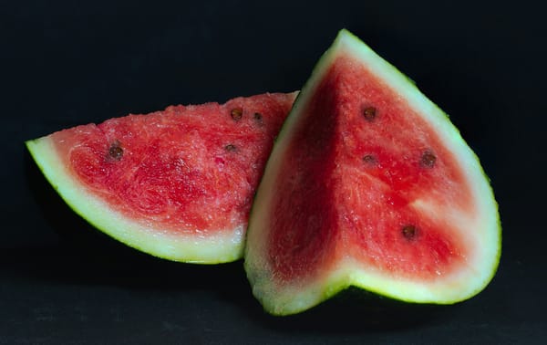 Two pieces of watermelon on a black background. 